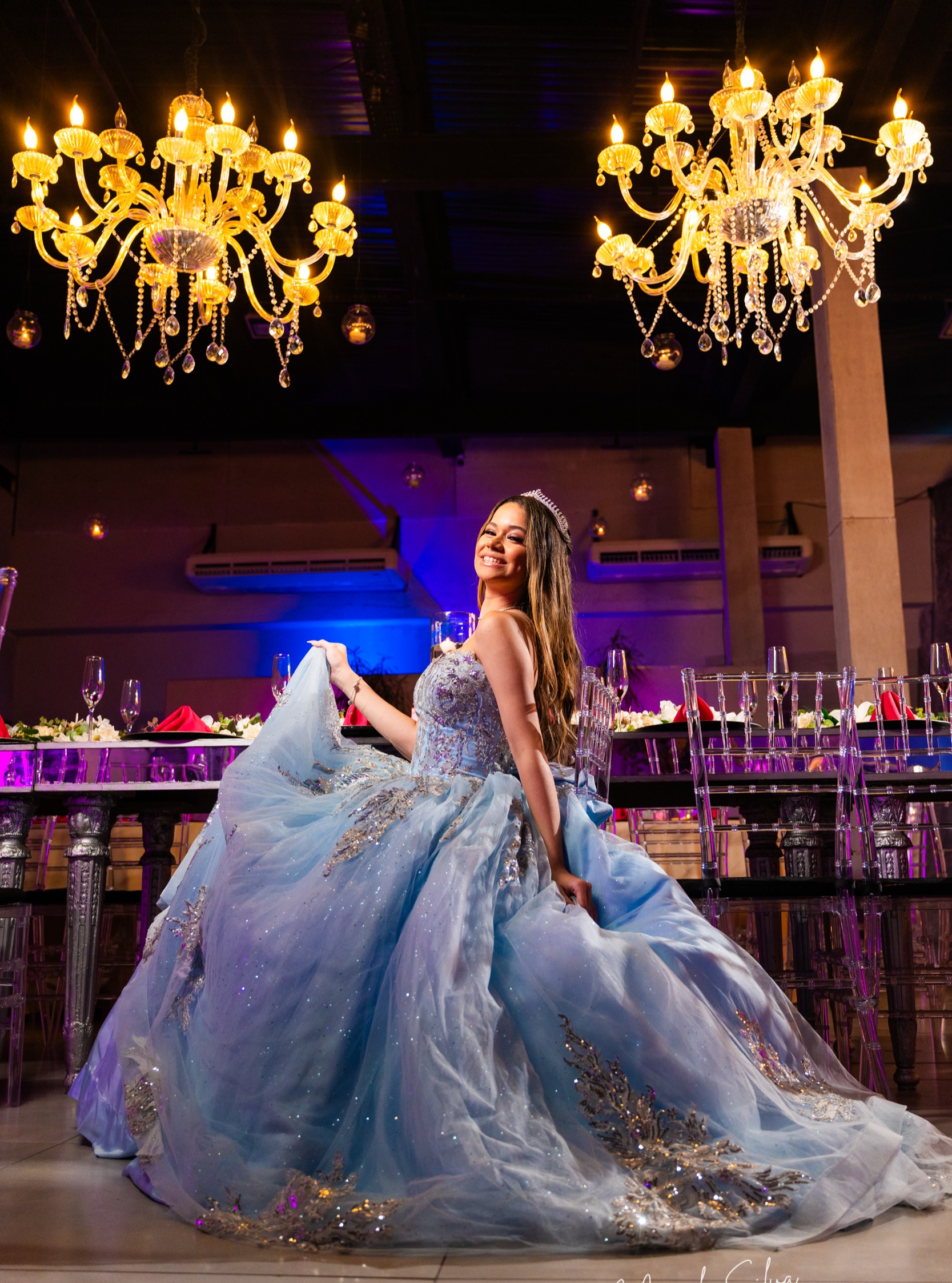 Debutante em vestido azul claro girando a saia sob candelabros dourados durante a festa de XV anos